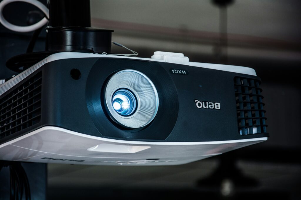 best budget projector 2026 showing NexiGo PJ40 Pro projector displaying a large screen image in a dark living room representing top affordable home theater projectors under 300 dollars