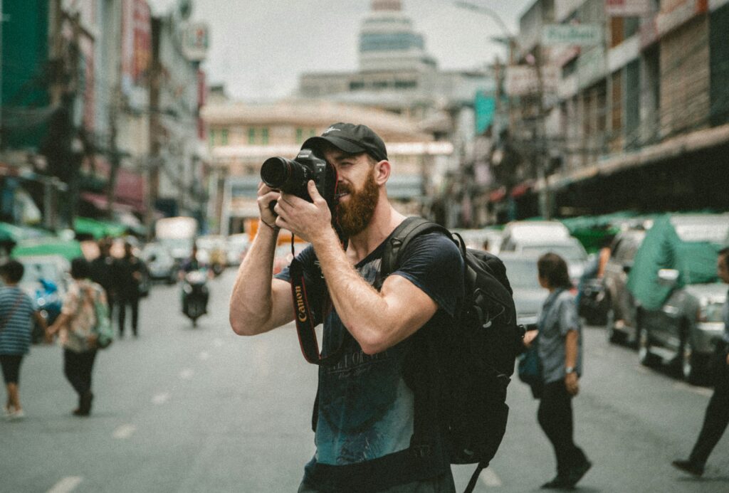 best camera for photography and video showing Sony A7 IV mirrorless camera with 24-70mm lens on wooden surface with camera bag in background