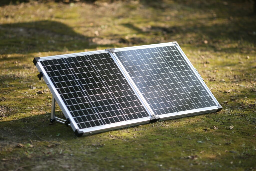 best portable solar charger showing BigBlue foldable solar panel and BLAVOR solar power bank laid out on a rock outdoors for camping and backpacking use